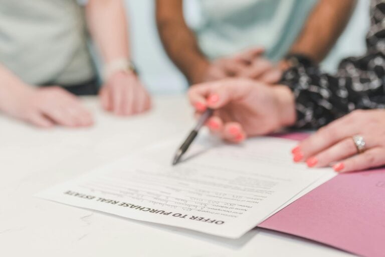 A person holding a ballpen on a white paper