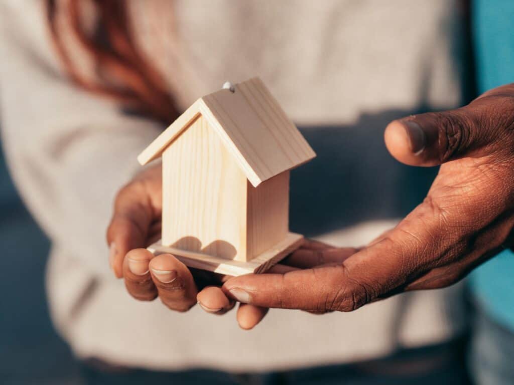 People holding a miniature wooden house